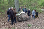 Eine Menschengruppe enthüllt im Wald einen Gedenkstein