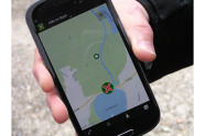 Nahaufnahme einer Hand mit Smartphone, auf dem die App "Hilfe im Wald" geöffnet ist (Foto: Michael Wolf).