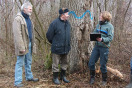 Försterin im Gespräch mit zwei Waldbesitzern. Im Hintergrund ein Biotopbaum.