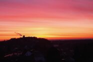 Blick von einem Hügel auf einen urbanen Hügel, im Hintergrund ein blutroter Sonnenuntergang