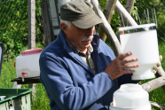 Älterer Mann mit weißen Plastegefäßen füllt Wasser um.