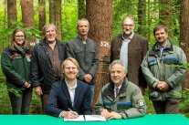 Guppenfoto von sieben Forstmännern und -frauen im Wald