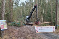 Abgesperrter Waldweg mit Holzerntemaschienen im Hintergrund