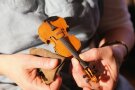 Eine kleine Geige wird mit einem Tuch poliert