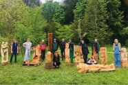 Eine Gruppe Menschen zeigt eine Gruppe aus Holz gearbeiteten Skulpturen