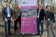 Gruppenbild der Teilnehmenden Hydrologen neben einem Aufsteller der Tagung.