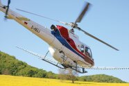 Hubschrauber über einem gelb blühendem Feld.