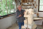 Ein Mann in einer Werkstatt arbeitet an einer Holzzkulptur