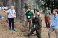 Personen stehen im Wald und bekommen eine Aktivität von einer Frau erklärt.