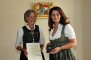 Zwei Frauen bei der Überreichung des Bundesverdienstkreuzes; links, die Empfängerin, eine alte Dame, rechts die Überreicherin, momentane bayerische Forstministerin