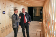 Zwei Männer stehen in einem Container voll mit Fakten über Holz und unterhalten sich.