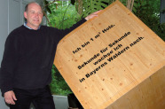 Prof. Peter Kolb steht nebem einem großen Holzwürfel