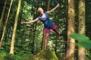 Eine Frau balanciert auf einem Baumstumpf mit einem Bein